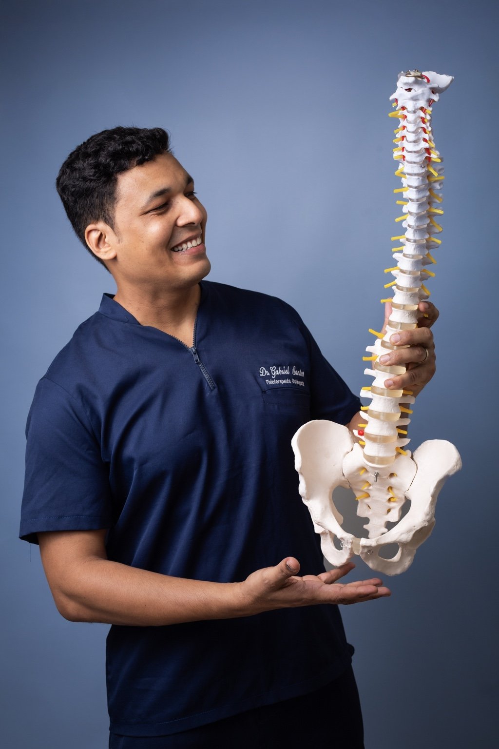 Dr. Gabriel Santos segurando um modelo anatômico de coluna